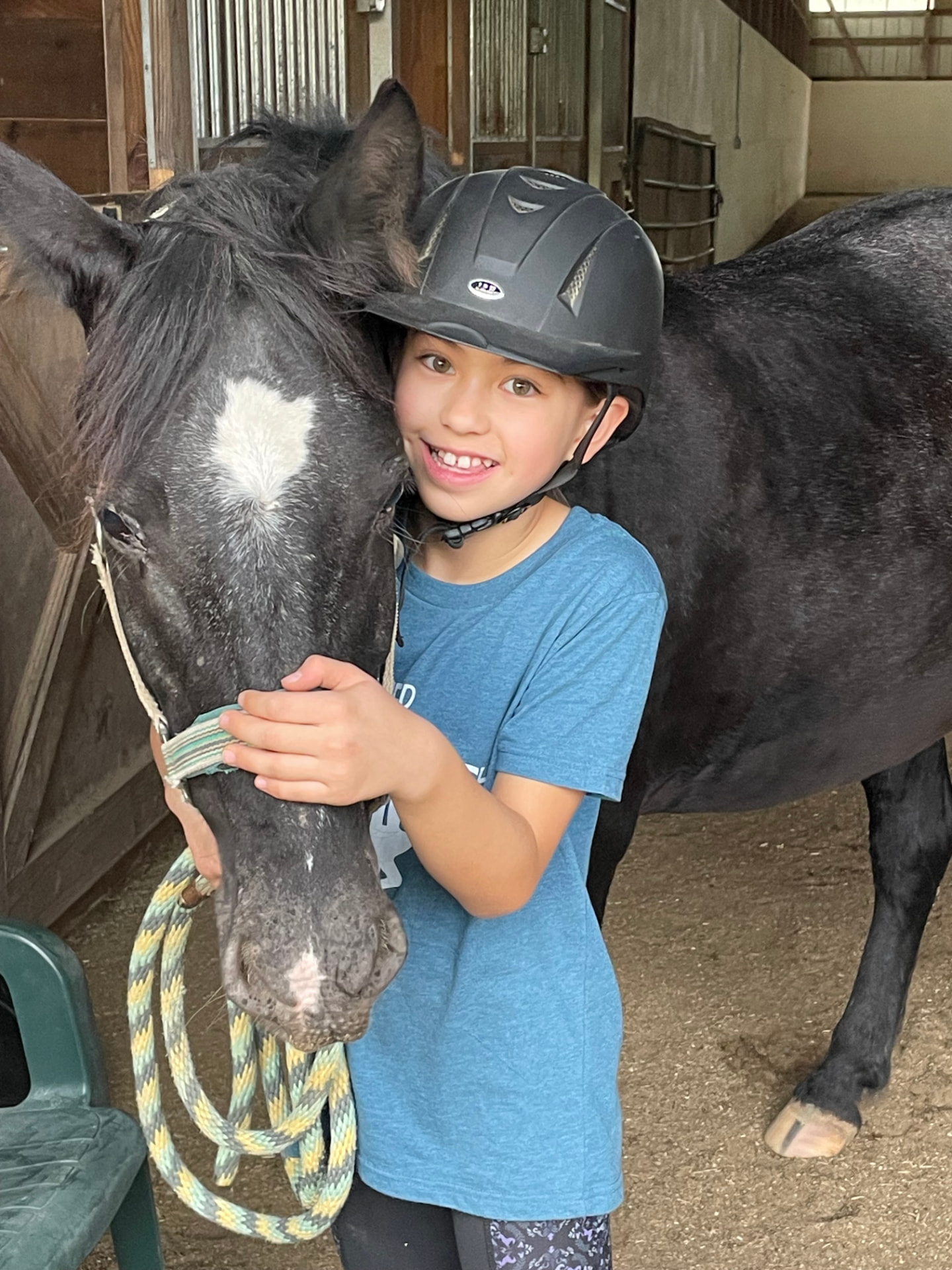 Young rider hugging a lesson horse in the barn